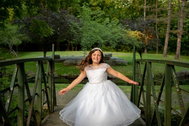 Outdoor portrait of a girl in a white dress on a garden footbridge, photographed by Simone Heffernan Photography